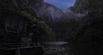 Movie still from “Jurassic Park III” (2001), directed by Joe Johnston – Two people in a boat on a body of water near a bridge; Extreme Wide shot, Low angle