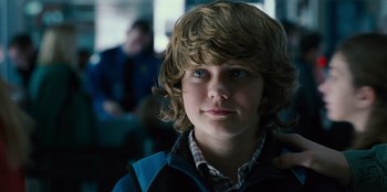 Movie still from “Jurassic World” (2015), directed by Colin Trevorrow – A young boy with blue eyes is looking into the camera; Close Up shot, Over the shoulder angle