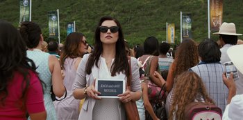 Movie still from “Jurassic World” (2015), directed by Colin Trevorrow – A woman holding up a sign in front of a group of people; Medium shot, High angle