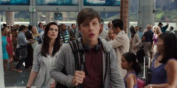 Movie still from “Jurassic World” (2015), directed by Colin Trevorrow – A man with headphones on walking through a crowd of people; Medium shot, Over the shoulder angle