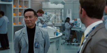 Movie still from “Jurassic World” (2015), directed by Colin Trevorrow – A group of people in a room with lab equipment; Medium shot, Over the shoulder angle