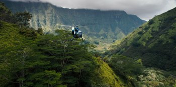 Movie still from “Jurassic World” (2015), directed by Colin Trevorrow – A helicopter flying over a lush green hillside; Extreme Wide shot, High angle