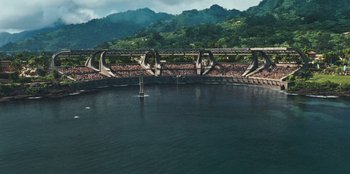 Movie still from “Jurassic World” (2015), directed by Colin Trevorrow – An aerial view of a bridge over a body of water; Extreme Wide shot, High angle