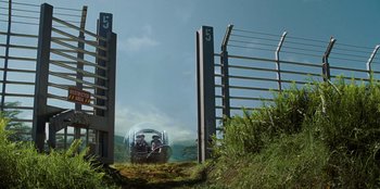 Movie still from “Jurassic World” (2015), directed by Colin Trevorrow – A train traveling through a lush green field; Extreme Wide shot, Low angle