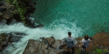 Movie still from “Jurassic World” (2015), directed by Colin Trevorrow – A man standing on a rock near a body of water; Extreme Wide shot, Overhead angle