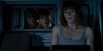 Movie still from “Jurassic World” (2015), directed by Colin Trevorrow – A woman sitting on a train next to two other people; Medium shot, Over the shoulder angle