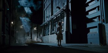 Movie still from “Jurassic World” (2015), directed by Colin Trevorrow – A woman standing on the side of the street at night; Extreme Wide shot, Low angle