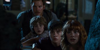 Movie still from “Jurassic World” (2015), directed by Colin Trevorrow – A group of people standing next to each other in a room; Medium shot, Low angle