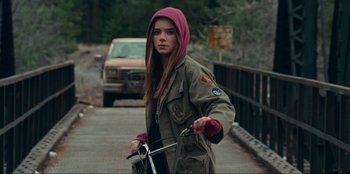 Movie still from “Jurassic World Dominion” (2022), directed by Colin Trevorrow – A young woman riding a bike down a street; Medium shot, Over the shoulder angle