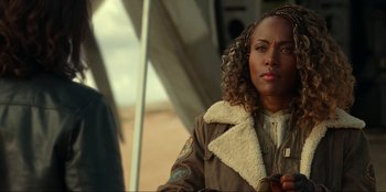 Movie still from “Jurassic World Dominion” (2022), directed by Colin Trevorrow – A woman in a brown jacket standing in front of an airplane; Close Up shot, Over the shoulder angle