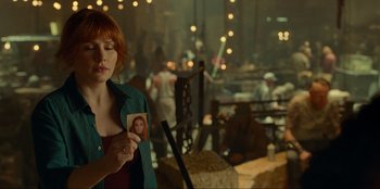 Movie still from “Jurassic World Dominion” (2022), directed by Colin Trevorrow – A woman holding a picture of herself in a dark room; Medium shot, Over the shoulder angle