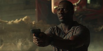 Movie still from “Jurassic World Dominion” (2022), directed by Colin Trevorrow – A man holding a gun while standing in a room; Close Up shot, Low angle