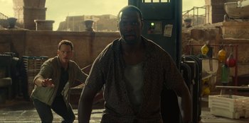 Movie still from “Jurassic World Dominion” (2022), directed by Colin Trevorrow – A man standing next to another man in a room; Medium shot, Low angle