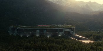 Movie still from “Jurassic World Dominion” (2022), directed by Colin Trevorrow – An aerial view of a bridge with a green roof; Extreme Wide shot, High angle