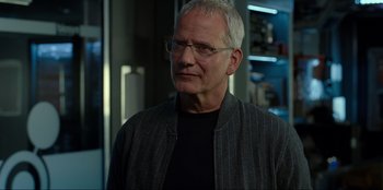 Movie still from “Jurassic World Dominion” (2022), directed by Colin Trevorrow – An older man wearing glasses and a striped jacket; Close Up shot, Over the shoulder angle