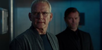 Movie still from “Jurassic World Dominion” (2022), directed by Colin Trevorrow – A man with glasses standing next to another man; Close Up shot, Over the shoulder angle