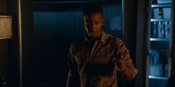 Movie still from “Jurassic World Dominion” (2022), directed by Colin Trevorrow – A man is holding a knife in a dark room; Medium shot, Low angle