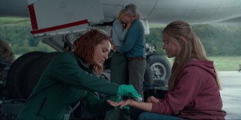 Movie still from “Jurassic World Dominion” (2022), directed by Colin Trevorrow – Two women are exchanging gifts in a garage; Medium shot, Over the shoulder angle
