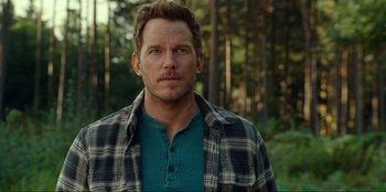 Movie still from “Jurassic World Dominion” (2022), directed by Colin Trevorrow – A man in a plaid shirt standing next to a forest; Close Up shot, Over the shoulder angle