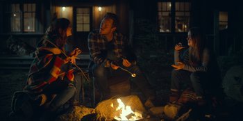 Movie still from “Jurassic World Dominion” (2022), directed by Colin Trevorrow – A group of people sitting around a fire pit at night; Medium shot, Over the shoulder angle