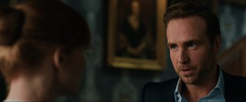 Movie still from “Jurassic World: Fallen Kingdom” (2018), directed by J.A. Bayona – A man in a suit and tie in front of a painting; Close Up shot, Over the shoulder angle