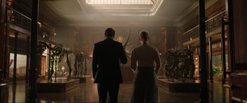 Movie still from “Jurassic World: Fallen Kingdom” (2018), directed by J.A. Bayona – A man and a woman standing in front of a wall of sculptures; Wide shot, Low angle