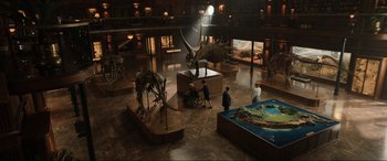 Movie still from “Jurassic World: Fallen Kingdom” (2018), directed by J.A. Bayona – A group of people standing in a room next to a dinosaur exhibit; Extreme Wide shot, High angle