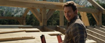 Movie still from “Jurassic World: Fallen Kingdom” (2018), directed by J.A. Bayona – A man standing in front of a wooden structure; Medium shot, Over the shoulder angle