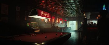 Movie still from “Jurassic World: Fallen Kingdom” (2018), directed by J.A. Bayona – Two people sitting at a table with a pool table; Extreme Wide shot, High angle