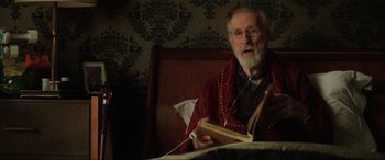 Movie still from “Jurassic World: Fallen Kingdom” (2018), directed by J.A. Bayona – An older man sitting in a bed reading a book; Close Up shot, Over the shoulder angle