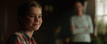 Movie still from “Jurassic World: Fallen Kingdom” (2018), directed by J.A. Bayona – A young girl smiling for the camera in a dark room; Close Up shot, Over the shoulder angle