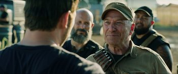 Movie still from “Jurassic World: Fallen Kingdom” (2018), directed by J.A. Bayona – A group of men standing next to each other on a field; Close Up shot, Over the shoulder angle