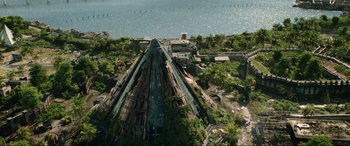 Movie still from “Jurassic World: Fallen Kingdom” (2018), directed by J.A. Bayona – An aerial view of an abandoned building near the water; Extreme Wide shot, Overhead angle