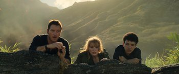 Movie still from “Jurassic World: Fallen Kingdom” (2018), directed by J.A. Bayona – A group of people sitting on top of a rock; Medium shot, Low angle