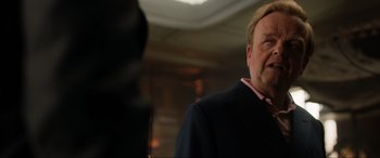 Movie still from “Jurassic World: Fallen Kingdom” (2018), directed by J.A. Bayona – A person wearing a suit and tie; Close Up shot, Over the shoulder angle