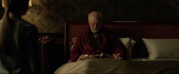 Movie still from “Jurassic World: Fallen Kingdom” (2018), directed by J.A. Bayona – An older man reading a book in bed; Medium shot, High angle