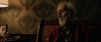 Movie still from “Jurassic World: Fallen Kingdom” (2018), directed by J.A. Bayona – An old man with a beard wearing glasses and a red shirt; Close Up shot, Over the shoulder angle