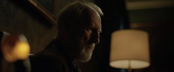 Movie still from “Jurassic World: Fallen Kingdom” (2018), directed by J.A. Bayona – An old man with a beard is looking into the light; Close Up shot, Over the shoulder angle