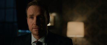 Movie still from “Jurassic World: Fallen Kingdom” (2018), directed by J.A. Bayona – A person wearing a suit and tie; Close Up shot, Over the shoulder angle