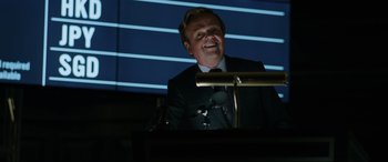 Movie still from “Jurassic World: Fallen Kingdom” (2018), directed by J.A. Bayona – A man standing at a podium in front of microphones; Close Up shot, Low angle