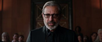 Movie still from “Jurassic World: Fallen Kingdom” (2018), directed by J.A. Bayona – An older man wearing a black suit and glasses; Close Up shot, Low angle