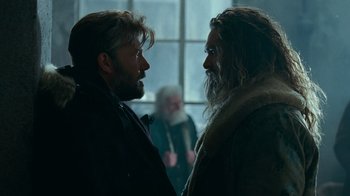 Movie still from “Justice League” (2017), directed by Zack Snyder – Two bearded men standing next to each other in front of a window; Medium shot, Over the shoulder angle