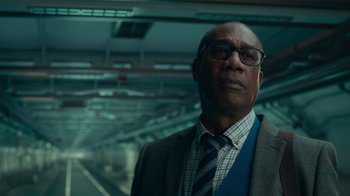 Movie still from “Justice League” (2017), directed by Zack Snyder – A man in a suit and tie standing in front of a train platform; Close Up shot, Low angle