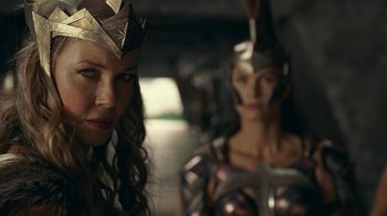 Movie still from “Justice League” (2017), directed by Zack Snyder – A woman wearing a paper crown next to another woman wearing a paper crown; Close Up shot, Low angle