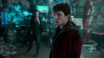 Movie still from “Justice League” (2017), directed by Zack Snyder – A man in a red and black jacket standing next to another man in a suit; Medium shot, Over the shoulder angle