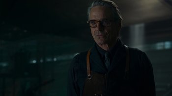 Movie still from “Justice League” (2017), directed by Zack Snyder – An older man wearing an apron in a dark room; Close Up shot, Over the shoulder angle