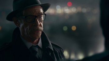 Movie still from “Justice League” (2017), directed by Zack Snyder – An older man wearing a hat and glasses; Close Up shot, Over the shoulder angle