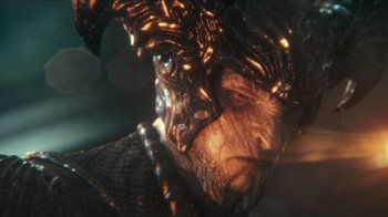 Movie still from “Justice League” (2017), directed by Zack Snyder – A man's face with a chain around his neck; Close Up shot, Over the shoulder angle