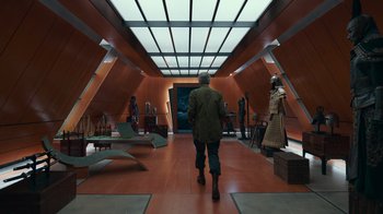 Movie still from “Justice League” (2017), directed by Zack Snyder – A man walking down a hall way in a building; Wide shot, High angle