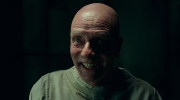 Movie still from “Justice League” (2017), directed by Zack Snyder – A man with a shaved bald head smiling for the camera; Close Up shot, Low angle